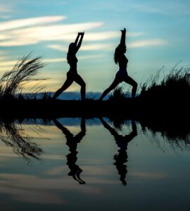 Two women doing yoga on the beach